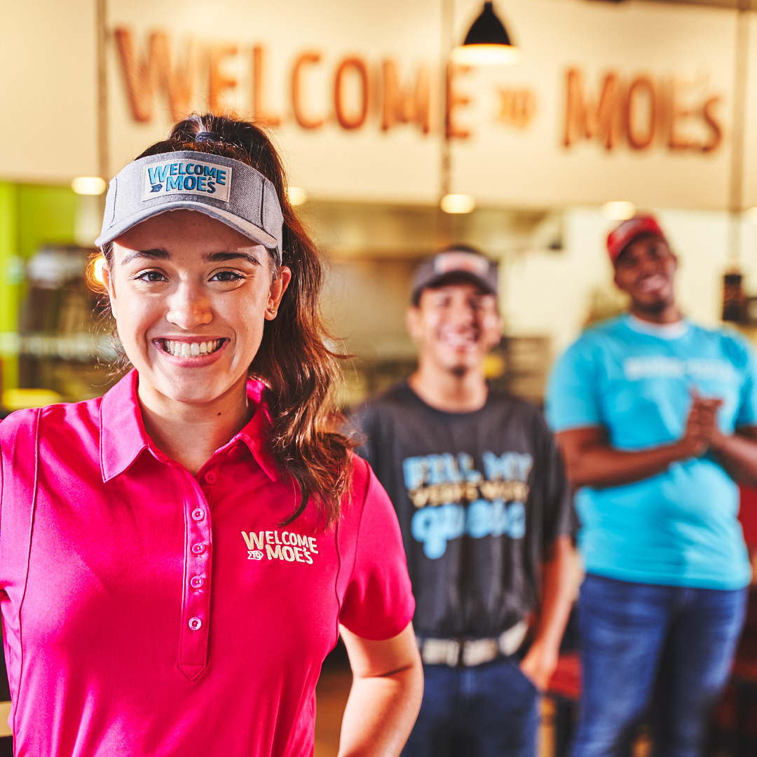Moe's team members smiling together in restaurant
